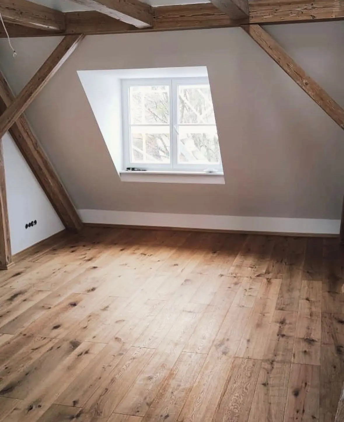 Ausgebautes Dachgeschoss mit freigelegten Holzbalken und Eichendielen