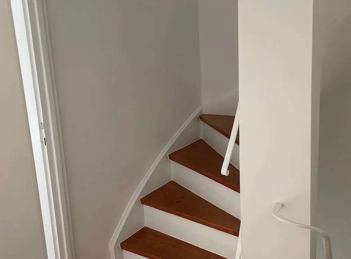 Sanierte Holztreppe mit weißem Geländer